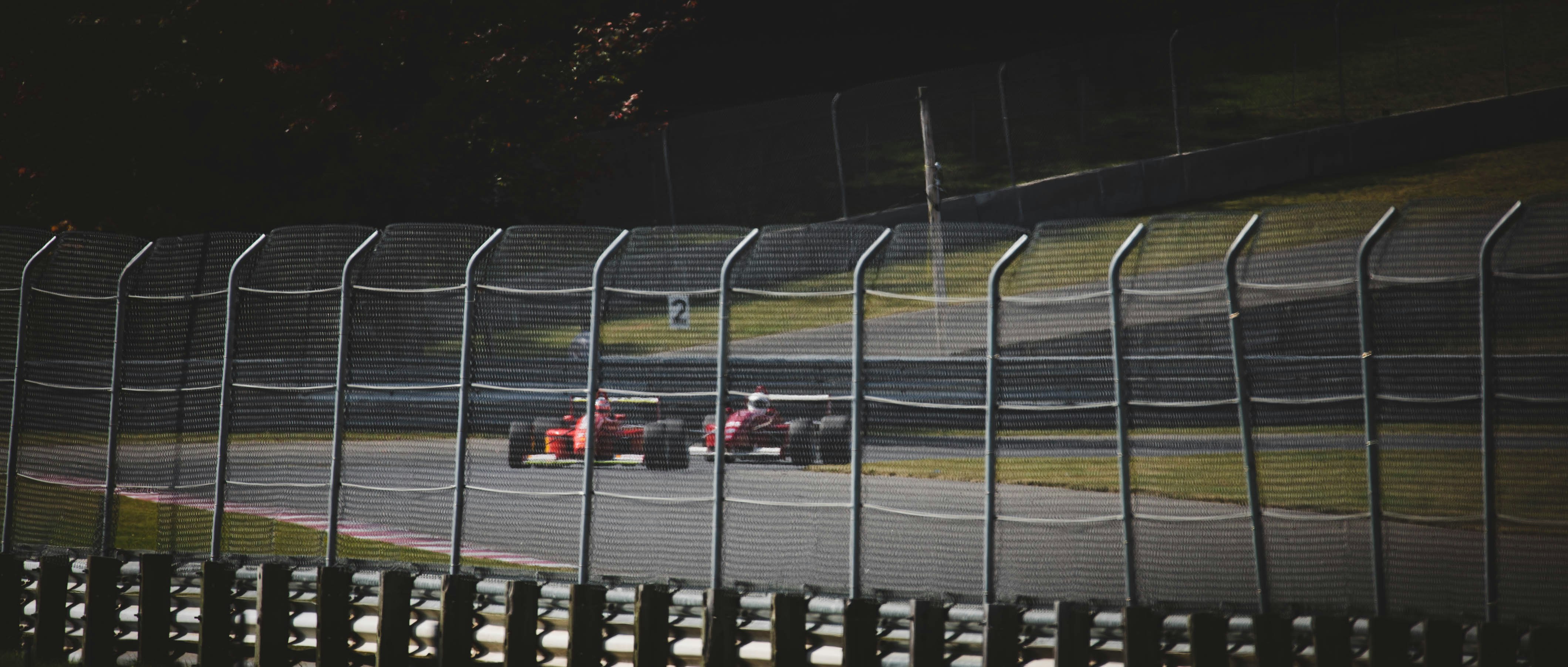 two red F1 cars on gray racetrack during daytime